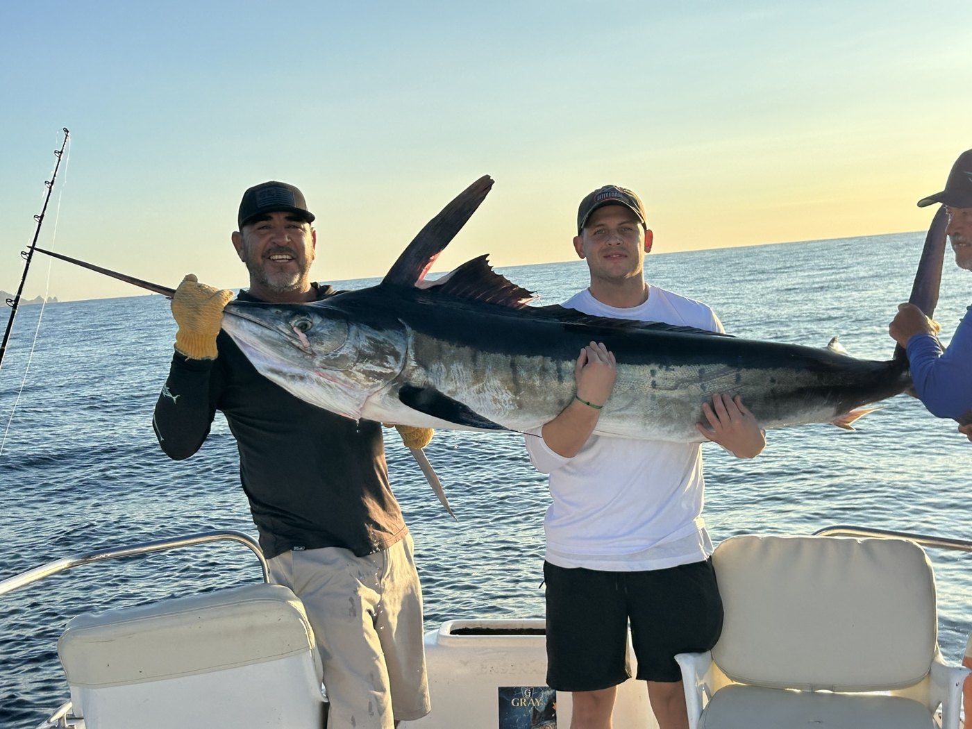 Anglers holding a marlin at sunset